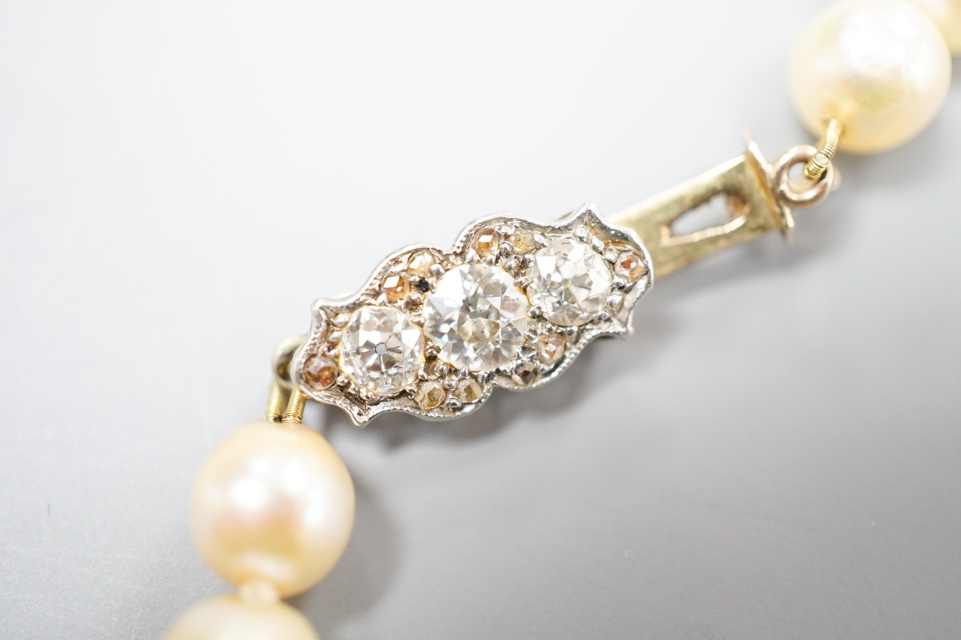 A single strand graduated pearl necklace (not tested for natural), with yellow metal and three stone diamond set clasp, 44cm.